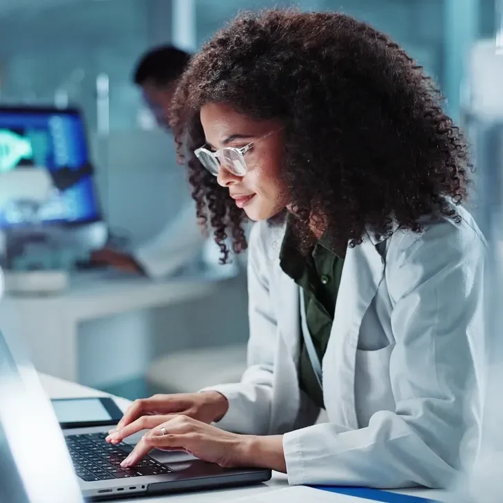 Female scientist working on a laptop in a lab.